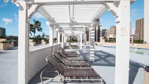 Un espace piscine aménagé sur le toit, avec des chaises longues et une structure en forme de pergola.