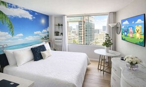 Habitación de hotel con cama, una mesa redonda, televisor y vistas a la ciudad.