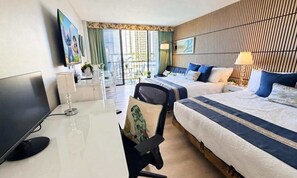 A hotel room with a desk, two beds, a TV, and a view of the outdoors.