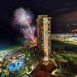 Een hotel met een zwembad, omringd door een strand en palmbomen.