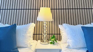 A neatly arranged bedroom with a modern lamp, a small plant, and a bed with white and blue pillows. - Waikiki Ocean View Studio, 3 Beds, Block to Beach (Honolulu)