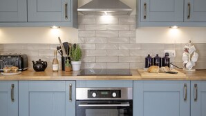 Een moderne keuken met lichtblauwe kastjes, een roestvrijstalen afzuigkap en een inbouwoven.