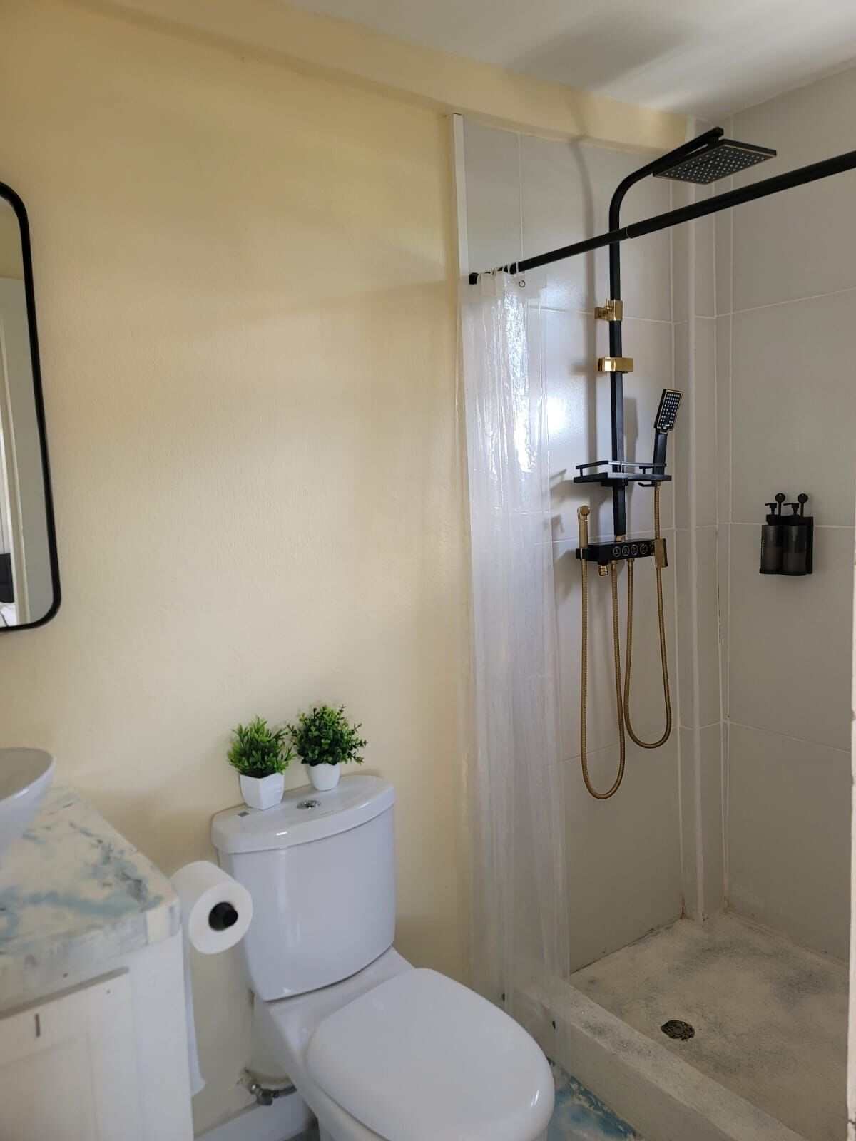 A bathroom with a toilet, a shower, and a sink.