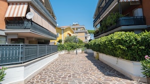 A narrow courtyard with stone flooring, bordered by buildings with balconies and satellite dishes. - LtPanella Jacqueline (Roma)
