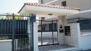 A building with a gated entrance, a covered patio, and a number '57' sign. - LtPanella Jacqueline (Roma)
