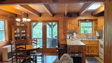 Un interior de cabaña espacioso con comedor, cocina y habitación en altillo.