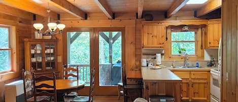 Interior espaçoso de cabana com área de refeições, cozinha e quarto no mezanino.