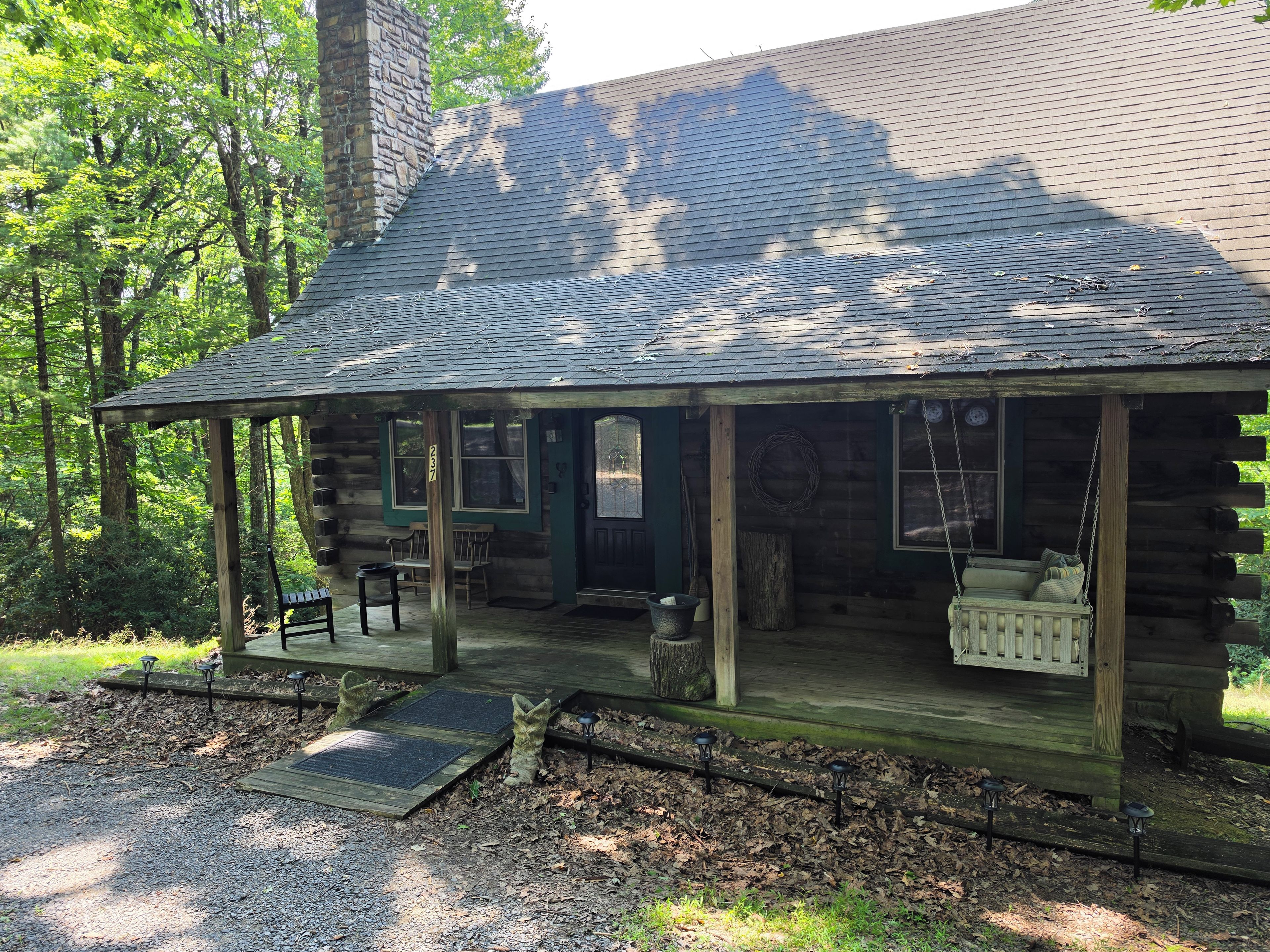 A rustic cabin with a porch, a swing, and a small outdoor seating area.