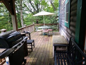 A wooden deck with a grill, a table with chairs, and an umbrella. - Lovely 2+bedroom Cabin in Fancy Gap, Coffey Grounds - Blue Ridge Parkway (Fancy Gap)
