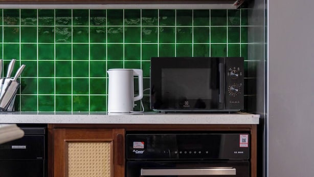 A kitchen with wooden cabinets, a microwave, a dishwasher, and a refrigerator. - Ho Tay Residences (Hanoi)