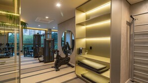 A modern gym with exercise equipment, a large mirror, and a glass wall offering a view of the outdoors. - Bothanic Campo Belo by Wecare Hosting (São Paulo)