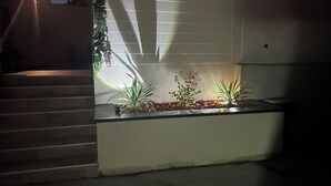 A modern outdoor planter with various plants and a small window above it. - THE NATURAL PATIO (Saint-Étienne)