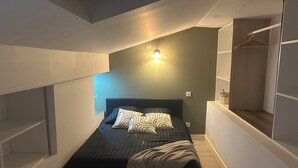 A compact bedroom with a bed, bedside shelving, and a small seating area. - THE NATURAL PATIO (Saint-Étienne)