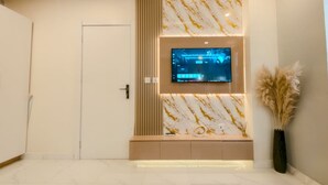 Een moderne hotellobby met een wand met marmerprint, een wandtelevisie en een decoratieve vaas.