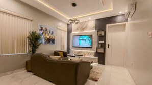 Een moderne woonkamer met een bank, televisie en decoratieve objecten.