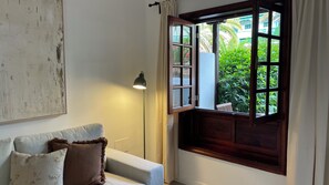A room with a white sofa, a lamp, and a window with a view of greenery. - The balconies of the Botanic Garden (Puerto de la Cruz)