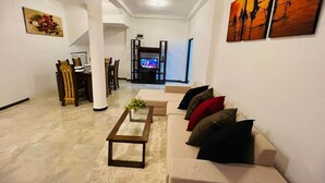 A spacious living room with a beige sofa, a coffee table, and a TV in the background. - Eolie Weligama (Weligama)