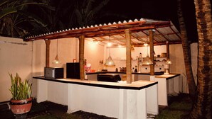 An outdoor kitchen area with a white countertop, hanging pendant lights, and a potted plant. - Eolie Weligama (Weligama)