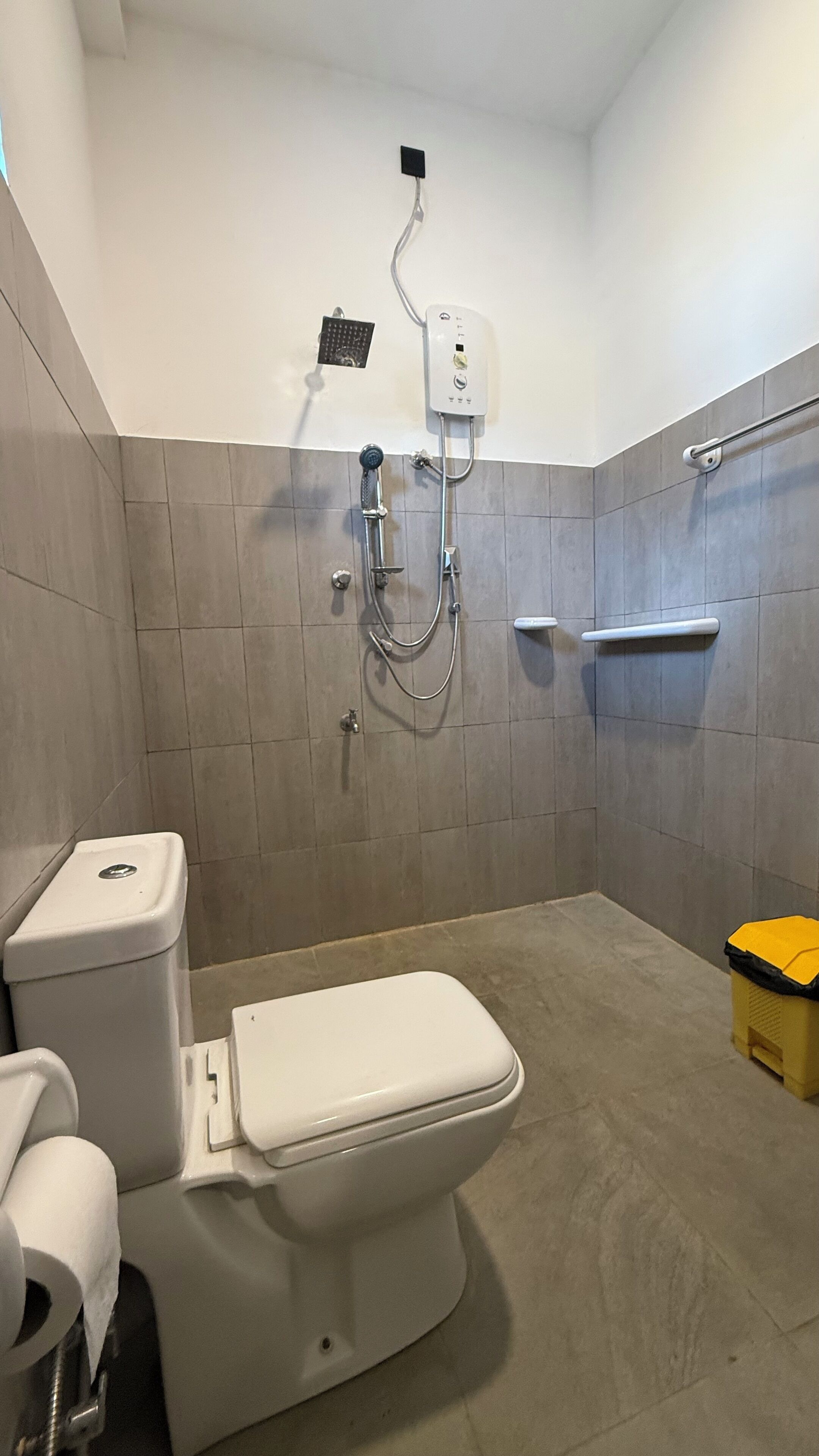 Un baño con inodoro, ducha y secador de manos.