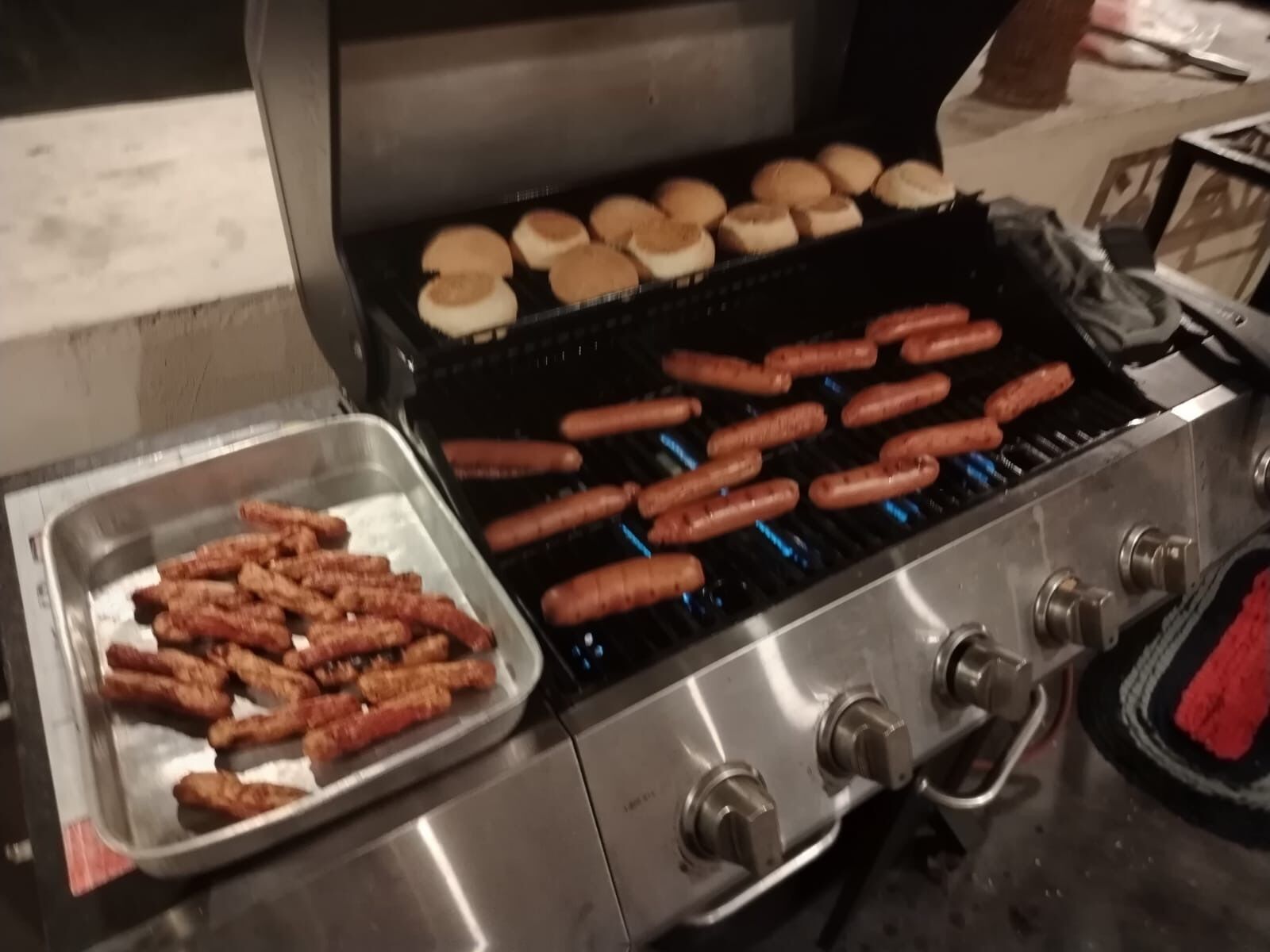 A grill with sausages and buns.