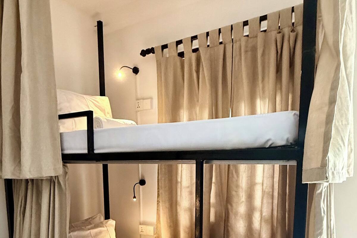 Habitación con literas, una mesita de noche y una lámpara.