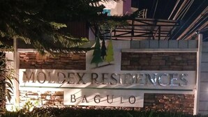 A sign for Moldex Residences in Bagulo, featuring a stone facade and illuminated text. - Cozy City Stay in Baguio (Baguio City)