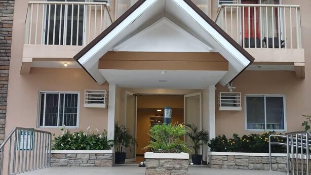 A multi-story building with a central entrance, stone steps, and potted plants. - Cozy City Stay in Baguio (Baguio City)