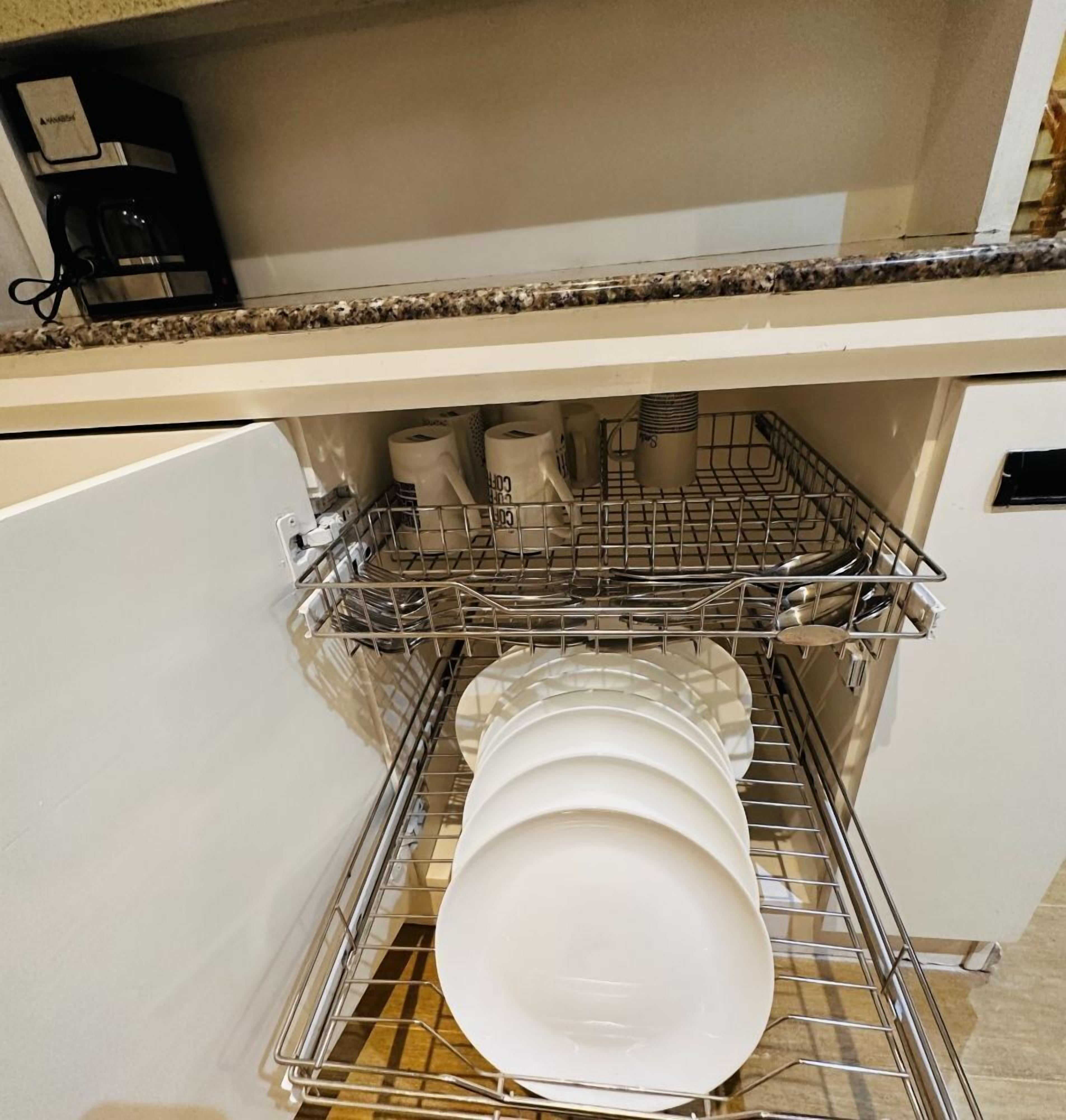Una cucina con lavastoviglie, piatti e tazze bianche.