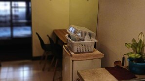 Une cuisine équipée d’un évier, d’un plan de travail, d’un petit réfrigérateur et d’une fenêtre avec des stores.