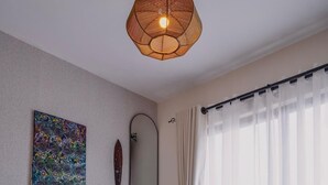 Ein modernes Schlafzimmer mit einem großen Bett, einer Nachttischlampe, einem wandmontierten Spiegel und einer Deckenleuchte.