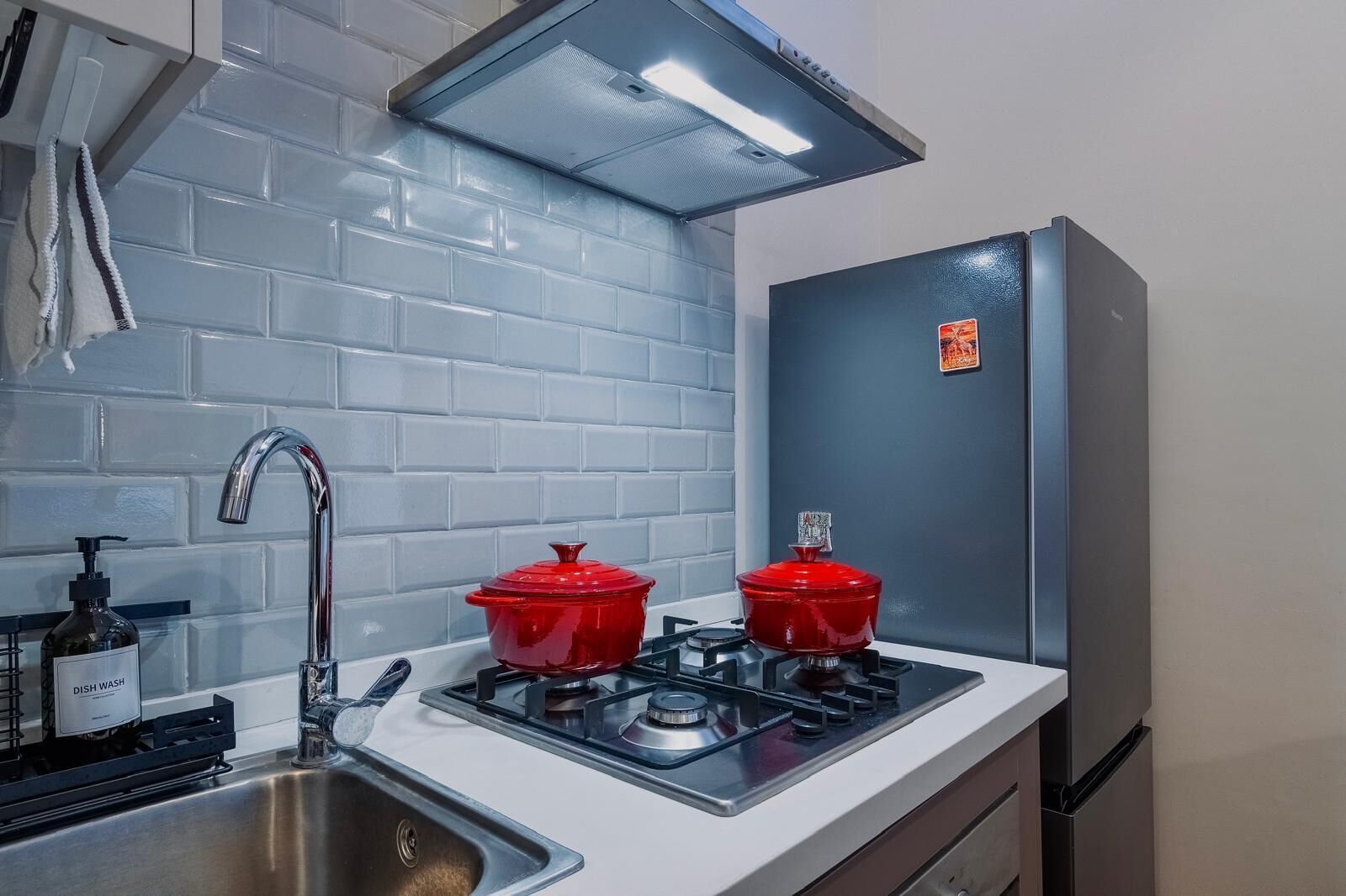 A kitchen with a stainless steel sink, a gas stove, and a refrigerator.