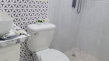 A bathroom with a toilet, a sink, and a shower enclosure.