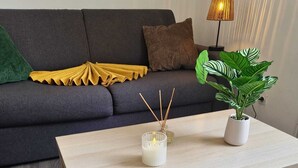 Een woonkamer met een bank, een salontafel, een lamp en een potplant.