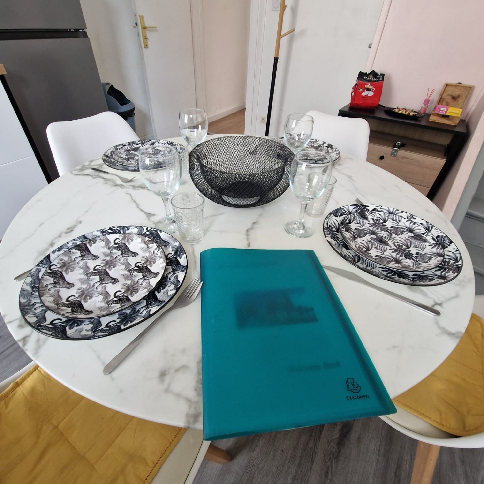 A dining table set with plates, glasses, and a menu.
