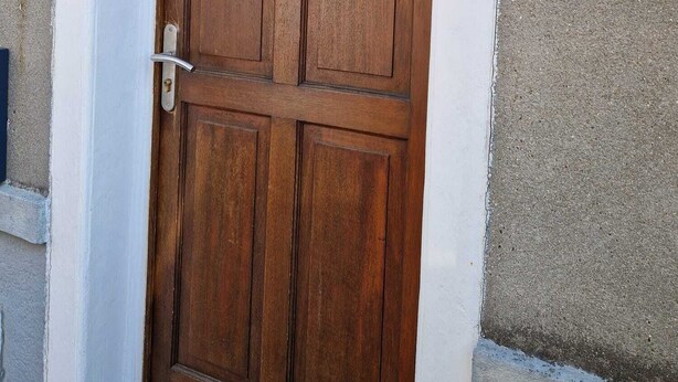 Een houten deur met een ruit en een brievenbus, nummer 40 op de muur.