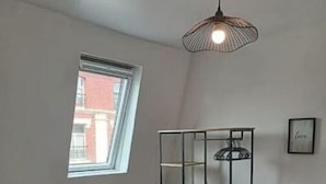 Een slaapkamer met een stapelbed, een raam, een radiator en een hanglamp.