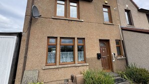 Et toetagers hus med brun facade, en fordør og tre vinduer.