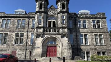 A historic stone building with a central arched entrance, two towers, and a red door.