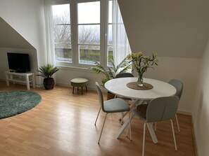 Un comedor con una mesa redonda, sillas grises y una planta en maceta.
