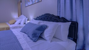 A hotel room with two beds, each with a headboard and multiple pillows.