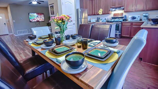 A dining area with a wooden table set for a meal, surrounded by chairs.
