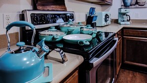 A kitchen with teal-colored appliances, including a stove, pots, and a kettle.
