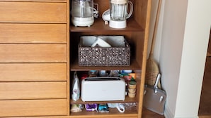 Eine Küche mit Küchenmaschine, Mixer, Toaster und verschiedenen Küchenutensilien in Regalen.