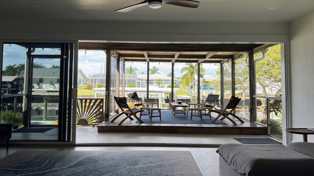 A spacious room with a large bed, a ceiling fan, and a balcony with chairs and a table.