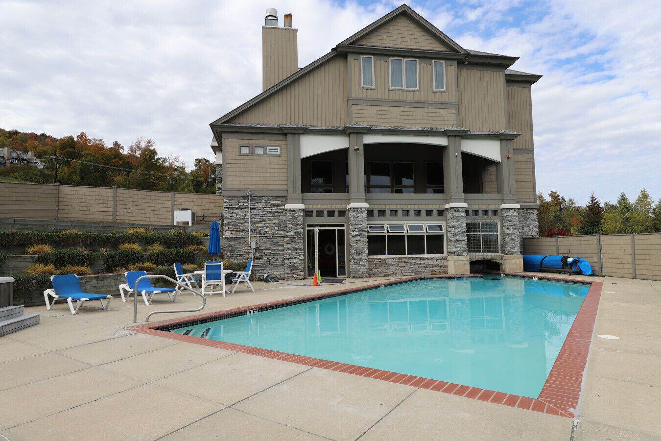 A two-story house with a swimming pool, stone accents, and a covered patio area.