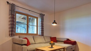 Un salon chaleureux avec un canapé, une table basse en bois et une fenêtre avec des rideaux.