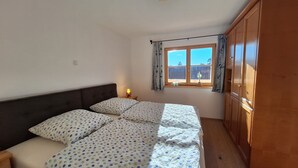Une chambre à coucher avec un lit, une table de chevet, une fenêtre avec des rideaux et des armoires en bois.