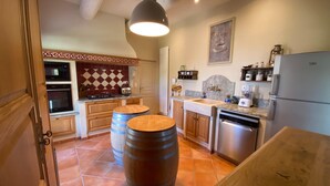 A kitchen with wooden cabinets, a marble backsplash, and a stainless steel refrigerator. - Farmhouse With Swimming Pool in Provence (Violes)