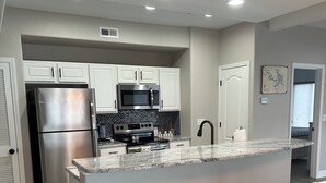 A modern kitchen with white cabinetry, stainless steel appliances, and a granite countertop.