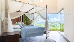 Ein Schlafzimmer mit Himmelbett, Blick ins Freie und einem großen Fenster.